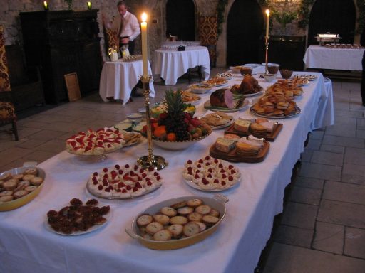 A long grand table in the Great Hall of Allington Castle set with a feast of foods and a large Christmas tree in the background.